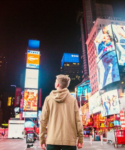 man standing on road infront of high-rise buildi