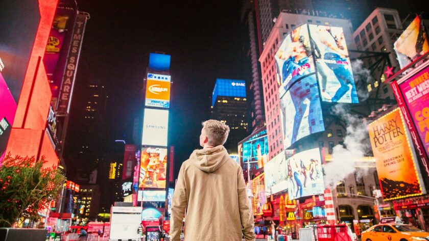 man standing on road infront of high-rise buildi