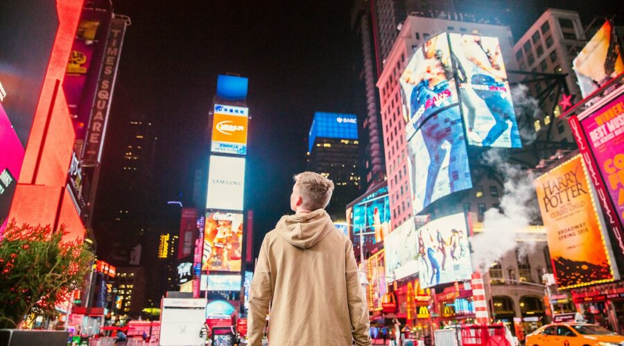 man standing on road infront of high-rise buildi