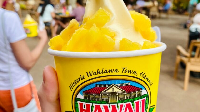 person holding a blue and yellow cup with yellow ice cream