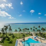 a pool and palm trees by the ocean